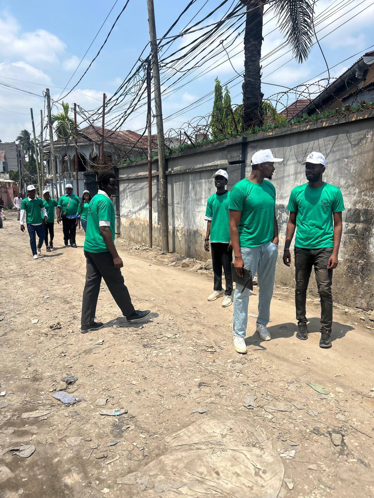 Membres de l’équipe Verdant en tee-shirt vert, discutant dans une rue d’un quartier de Kinshasa